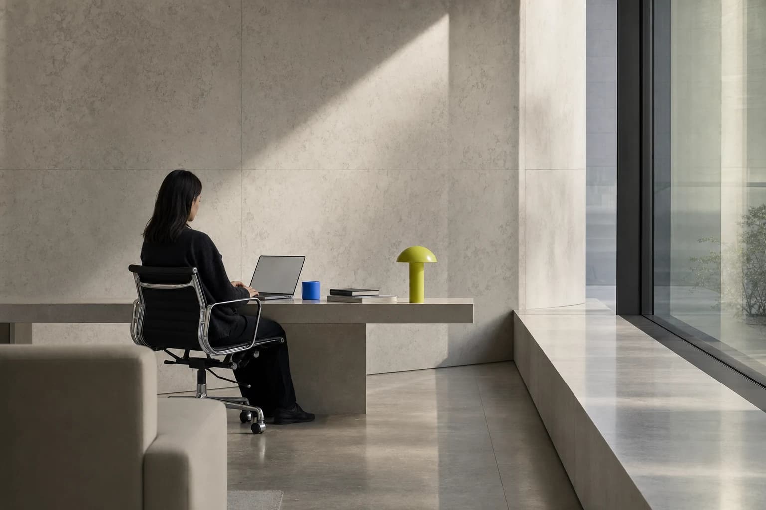 A small-team workspace with one person working beside a sunlit window